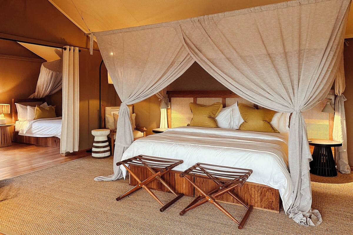 A room with a canopy bed, a small table, and a chair.