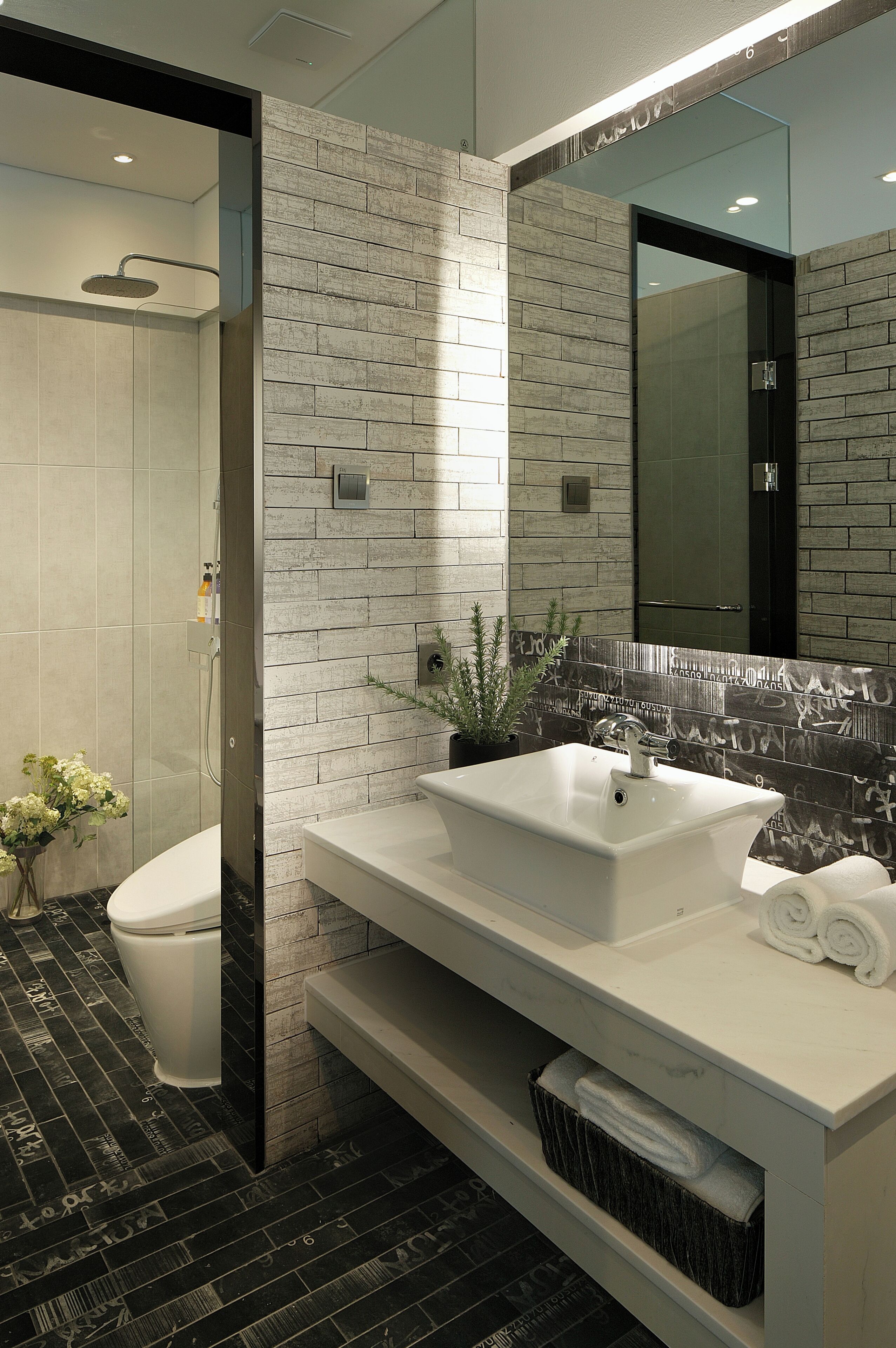 Un bagno moderno con doccia, WC e un ampio specchio.