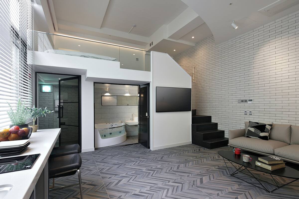 A modern living space with a kitchen, dining area, and a seating area with a sofa and coffee table.