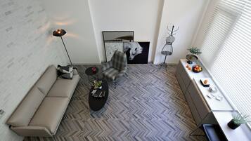 Una sala de estar moderna con un sofá, un sillón y una mesa de centro, un suelo con estampado de espiga y una obra de arte en la pared.