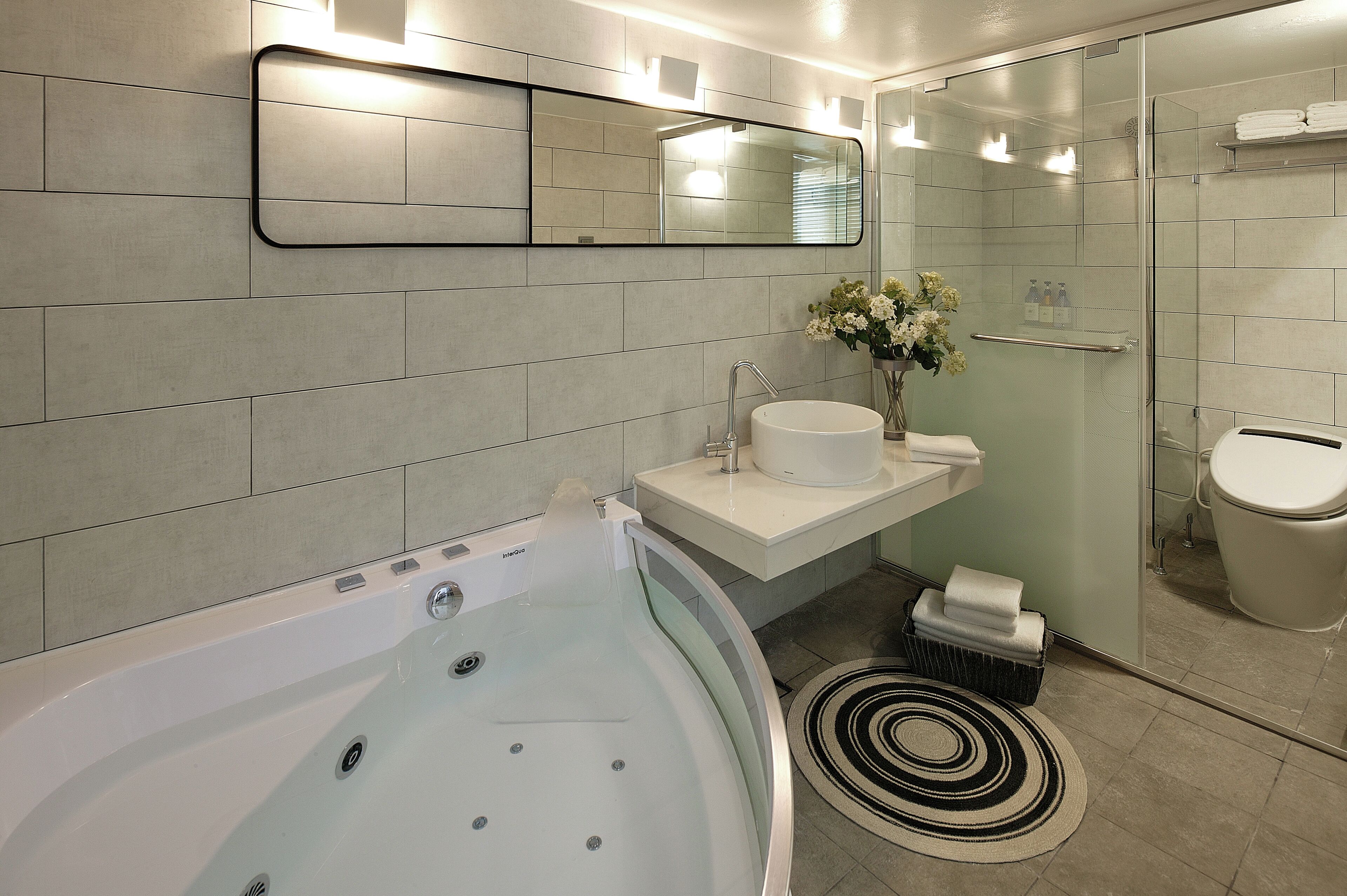 Ein modernes Badezimmer mit einer Badewanne, einem Waschbecken, einem Spiegel und einer Dusche.