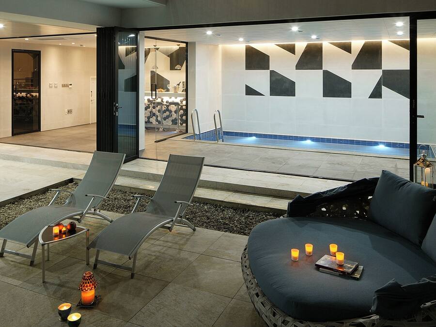 A modern outdoor seating area with lounge chairs, a fire feature, and a pool in the background.