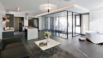 Un interior moderno con cocina, comedor y un balcón con cerramiento de vidrio.