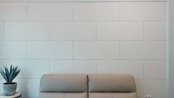 Una habitación moderna con un ventanal grande, un sofá y una pequeña mesa con una planta.
