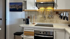 Een moderne keuken met witte kasten, een roestvrijstalen afzuigkap en een betegelde spatwand.