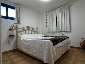 A bedroom with a bed, a bedside lamp, a window with curtains, and a radiator. - La Petite Foret Sea-view Apartment in Mascarat (Altea)