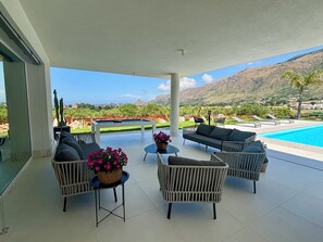 A covered outdoor area with a pool, seating, and a view of mountains. - Villa Nanni, Contemporary, Pool and Garden (Sicilia)