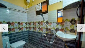 Een badkamer met toilet, wastafel, douche en decoratieve bloementegels.