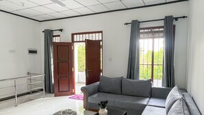 A spacious living room with a grey sofa, a coffee table, and a ceiling fan. - Rivora 2-Bedroom Apartment in Aluthgama Near Bentota Beach (Aluthgama)