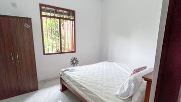 A bedroom with a bed, a wardrobe, a window, and a ceiling fan.