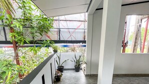 A covered corridor with potted plants, tiled flooring, and a view of the outside through a window. - Rivora 2-Bedroom Apartment in Aluthgama Near Bentota Beach (Aluthgama)