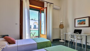Ein Zimmer mit zwei Betten, einem Schreibtisch mit Stuhl, einem Fenster mit Vorhängen und Blick auf ein Gebäude.