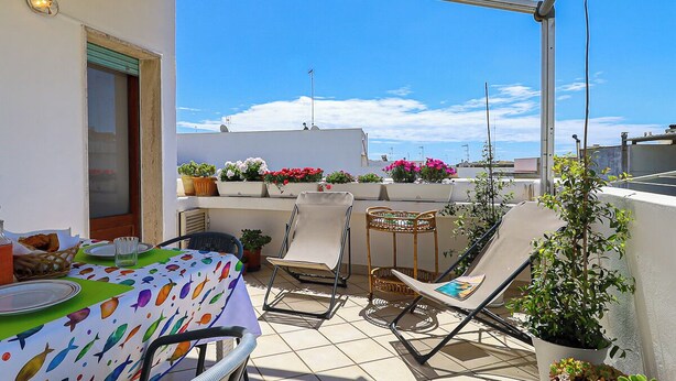 Eine Dachterrasse mit Esstisch, Lounge-Sesseln und Topfpflanzen.