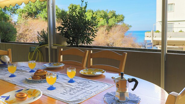 A dining table with breakfast items, a view of the sea, and a yellow awning. - Casa sul mare Rivabella by Casa di Marco (Rivabella)