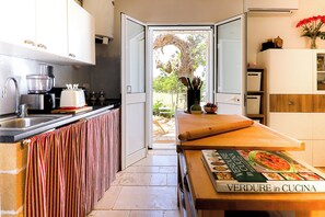 A modern kitchen with a view to the garden, featuring a sink, stove, and a book titled "Verdure in Cucina". - La Beccaccia by Casa di Marco (La Corte)