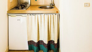 A compact kitchen with a wooden shelf above the counter, a small sink, and a stove. - Maria nel Casale Mastria by Casa di Marco (Neviano)