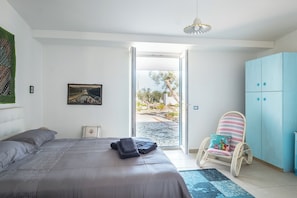 Una camera da letto con un letto, una sedia, un armadio e una porta che dà su uno spazio esterno.