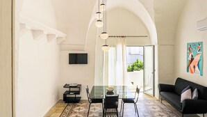 A modern interior with a glass dining table, black chairs, a black sofa, and a ceiling light fixture. - Palazzo Frascà by Casa di Marco (Parabita)