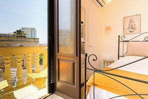 Ein Schlafzimmer mit Bett, Tür, Fenster und Blick ins Freie.