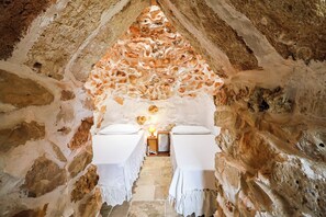 Una habitación con pared de piedra y cama blanca con dosel blanco.