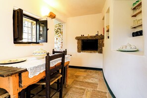 Un coin repas rustique avec un mur en pierre, une table en bois et des chaises.