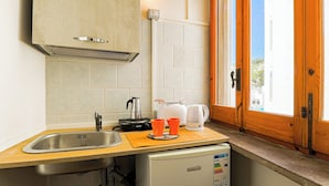 Ett litet, praktiskt kök med en diskho, ett litet kylskåp, en kaffebryggare och en brödrost.