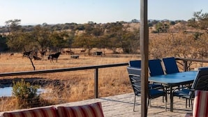 A terrace with outdoor seating, a view of wildlife, and a natural landscape. - Casa de la Presa 1 (Polokwane)