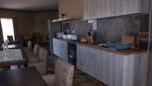 A compact kitchen with a central island, built-in cabinets, and a dining area with a table and chairs. - Casa de la Presa 1 (Polokwane)