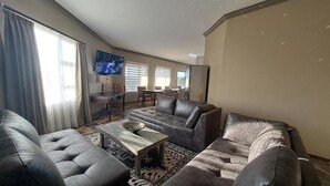 A living room with a sofa set, a coffee table, and a TV mounted on the wall. - Casa de la Presa 1 (Polokwane)