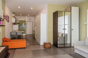 Ein modernes Wohnzimmer mit einer Couch, einem Hocker und einem Essbereich mit Stühlen und einem Tisch.