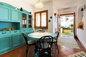 Un coin repas avec des meubles de couleur turquoise, une table ronde et des chaises noires.