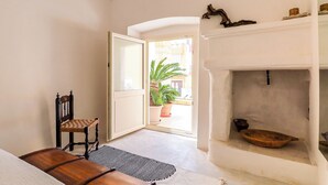 Una habitación con un banco de madera, una silla, una chimenea y vistas al exterior.