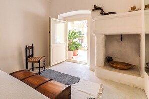 Una stanza con una panca di legno, una sedia, un caminetto e vista sull'esterno.