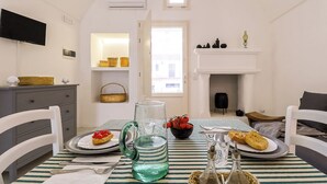 Comedor con mantel a rayas, una jarra, un cuenco de fruta y platos con comida.
