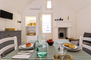 Un'area pranzo con tovaglia a righe, un boccale, una ciotola di frutta e piatti con cibo.