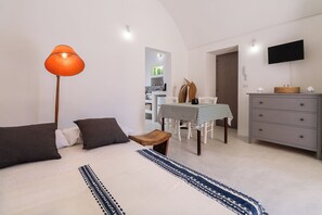 Quarto moderno com cama, mesa de cabeceira, luminária, cômoda e um espaço de refeições com cadeiras e mesa.