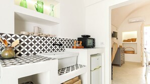 Een keuken met een zwart-wit betegelde spatwand, een magnetron, een spoelbak en een koelkast.