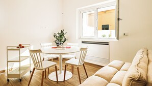 Un comedor con una mesa redonda, cuatro sillas, una planta y una ventana con persianas.