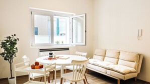 Un comedor moderno con una mesa redonda, sillas blancas y un sofá color beige.