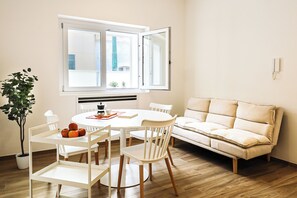 A modern dining area with a round table, white chairs, and a beige sofa. - Umberto I/2 by Casa di Marco (Sannicola)