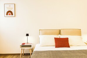 A neatly arranged hotel room with a bed, pillows, a nightstand, a lamp, and a framed picture on the wall. - Umberto I/2 by Casa di Marco (Sannicola)