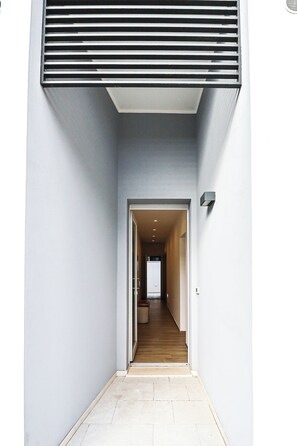 A narrow hallway with a wooden floor leading to a room with a bed and a nightstand. - Umberto I/2 by Casa di Marco (Sannicola)