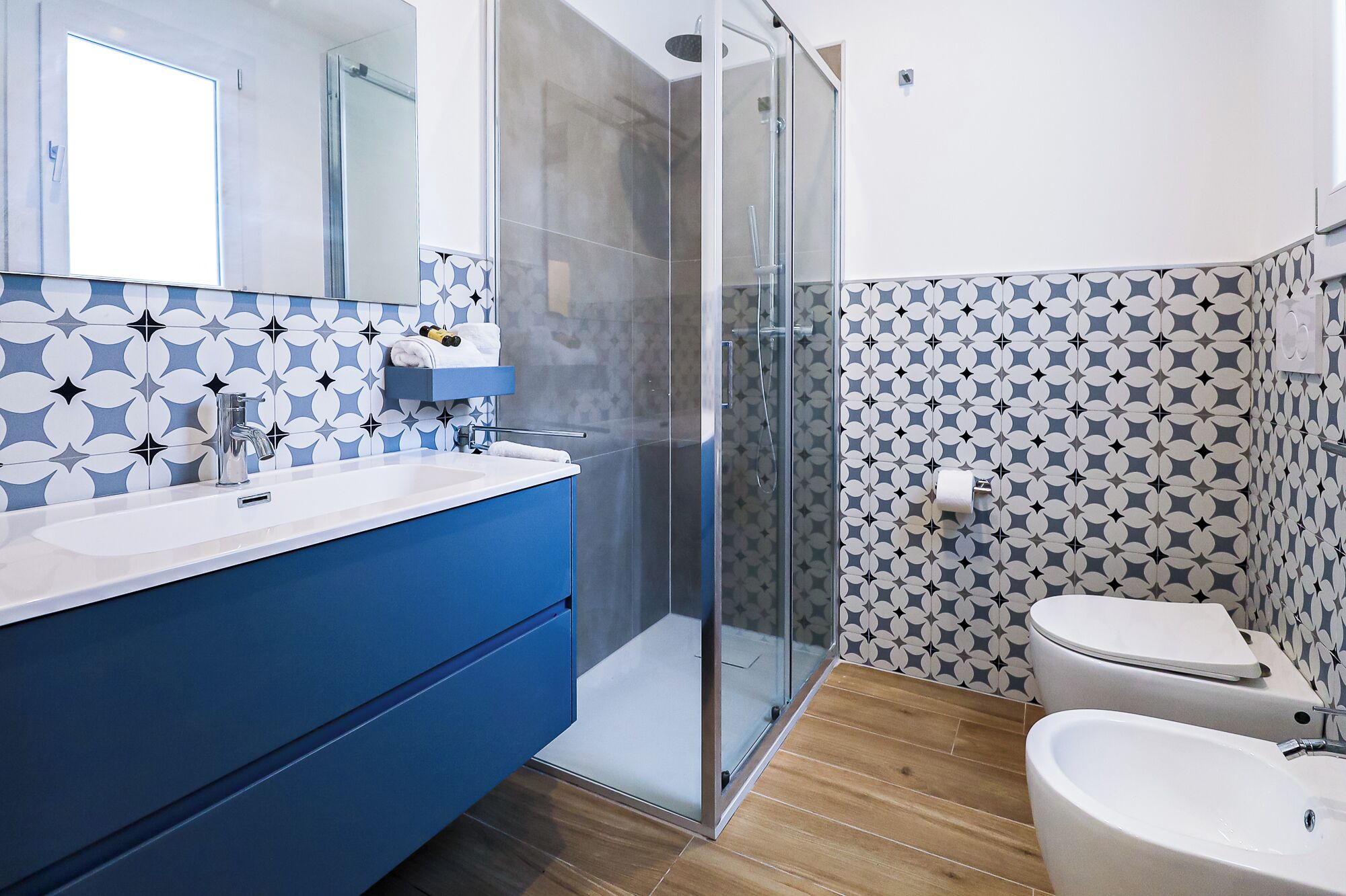 A modern bathroom with a glass shower enclosure, a white sink, and a toilet.