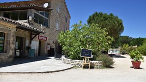 Un bâtiment en pierre avec une enseigne indiquant « ÉPICERIE » et un panneau noir annonçant la présence d’un restaurant.