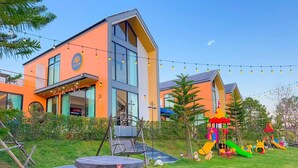 En moderne bygning med store vinduer og et legeområde med farverigt udstyr.