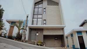 A modern two-story building with a flat roof, large windows, and a brick facade. - Villa Verde: Relax, Unwind & Stay in Spacious Comfort (Muntinlupa)