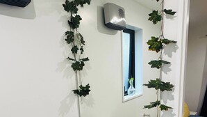 A bathroom with a white sink, black countertop, and a mirror with ivy decorations. - Room-room With En-suite and Kitchenette (Kaiapoi)