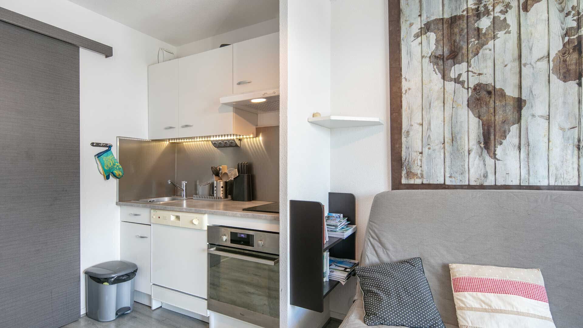 Una cocina compacta con electrodomésticos modernos, un comedor con mesa y sillas, y una gran obra de arte de madera en la pared.
