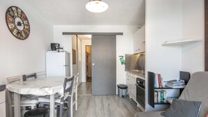 A compact living space with a dining area, kitchenette, and a seating area with a television. - Charming studio apartment, sleeps 6-7, mountain view (Chamrousse)