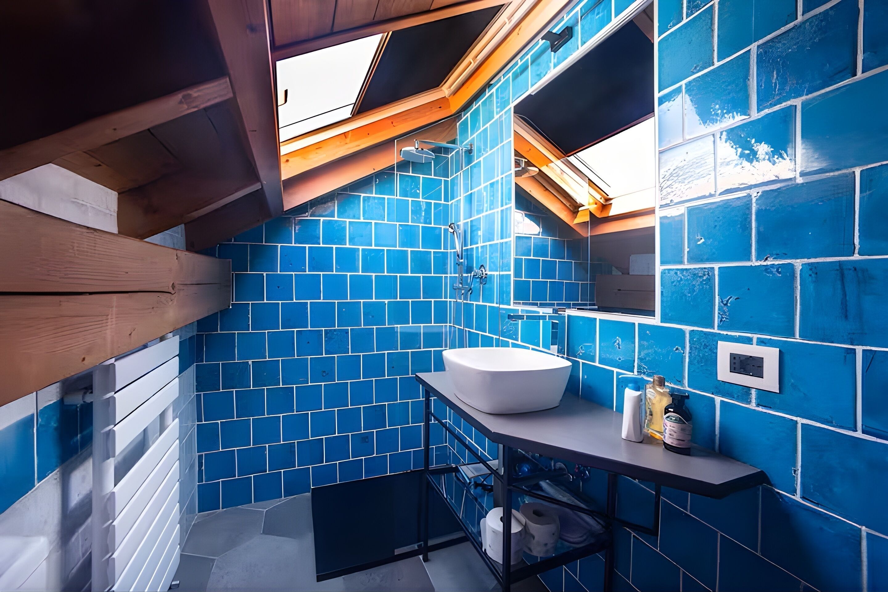 Un baño con azulejos azules, un lavamanos blanco y un tragaluz.